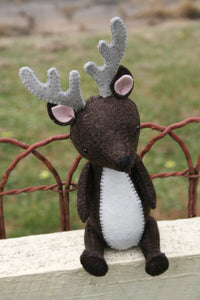 felt deer sitting on a fence