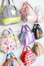 Load image into Gallery viewer, bitty bowler sewing pattern bags hanging on a wall
