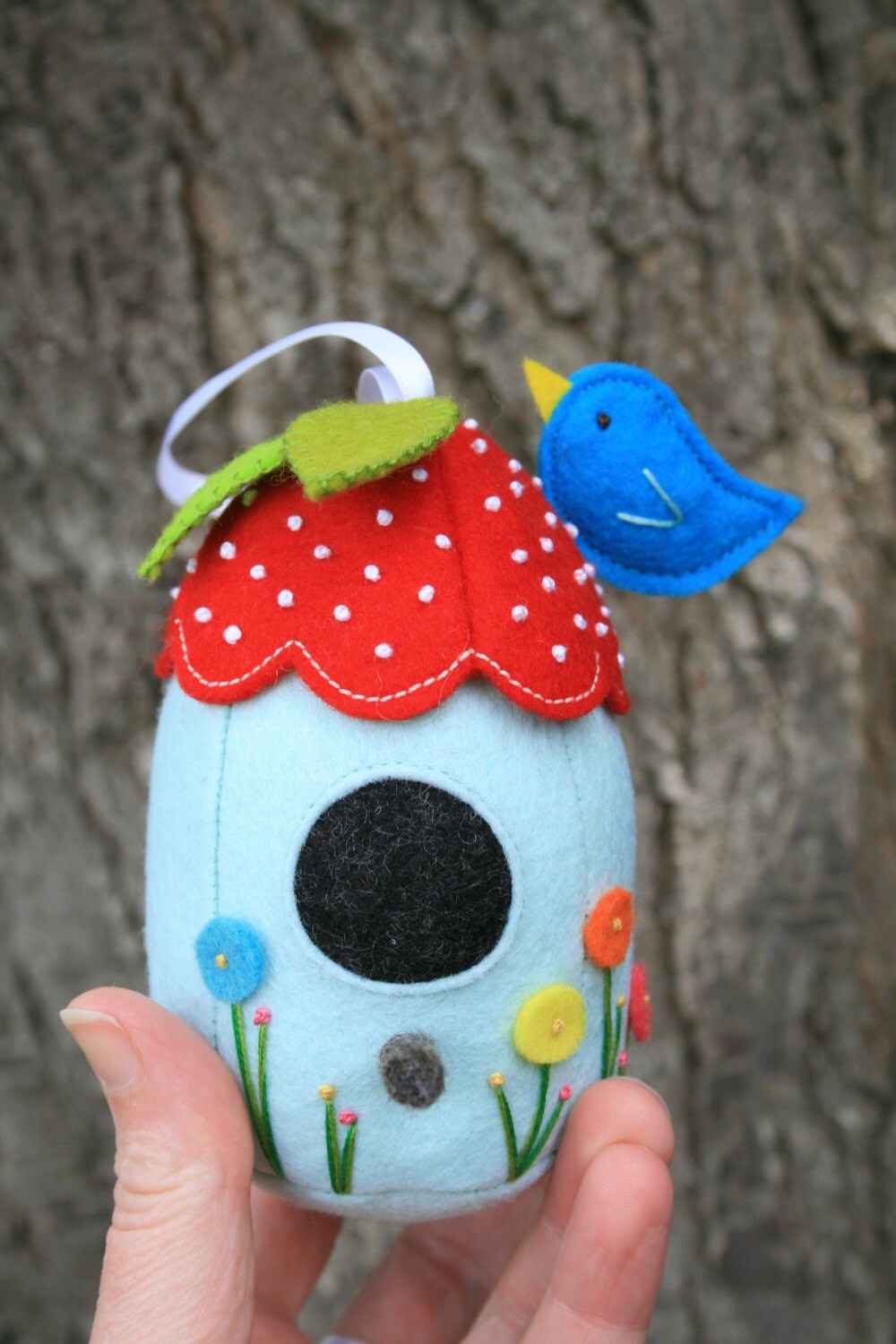 hand holding a felt birdhouse pincushion