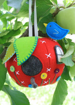 Load image into Gallery viewer, red felt apple shaped pincushion decorated like a house with embroidered flowers and a bluebird pin
